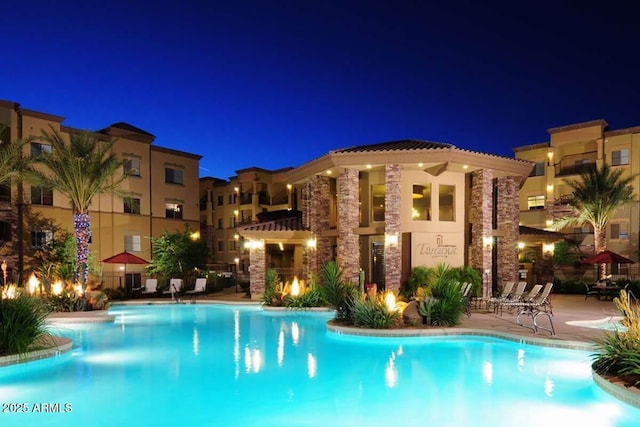 pool at twilight with a community pool and a patio area