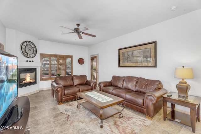 living area with baseboards, a multi sided fireplace, and ceiling fan