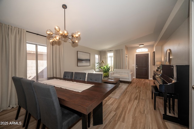 dining room with lofted ceiling, a notable chandelier, and light hardwood / wood-style flooring