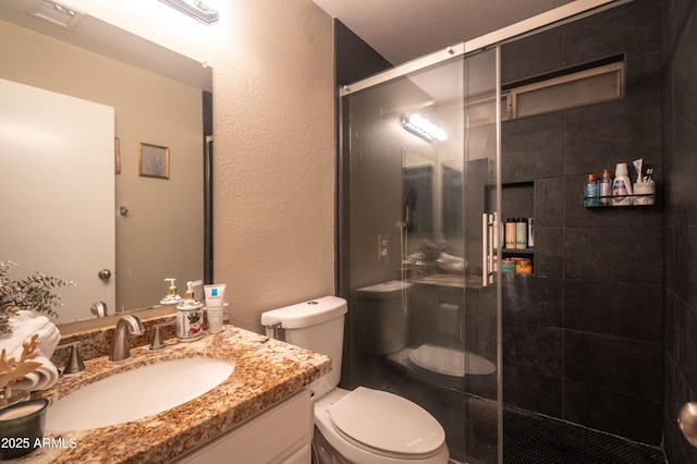 bathroom featuring vanity, toilet, and a shower with door