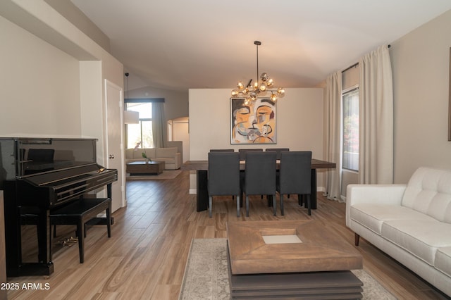 living room with a chandelier, vaulted ceiling, and light wood-type flooring