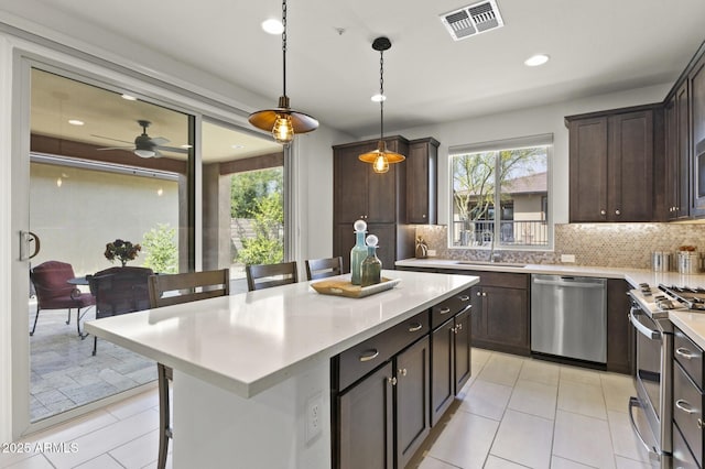 13204 W Via Dona Rd, Peoria, AZ 85383 - kitchen featuring light countertops, tasteful backsplash, a kitchen breakfast bar, appliances with stainless steel finishes, and visible vents