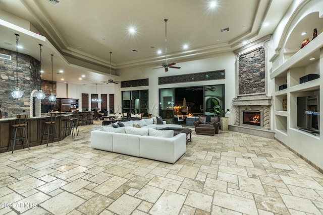 living room featuring built in features, light tile patterned floors, a large fireplace, ceiling fan, and a towering ceiling