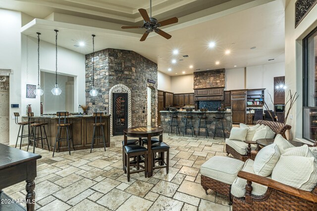 living room with a high ceiling, ceiling fan, ornate columns, and a raised ceiling