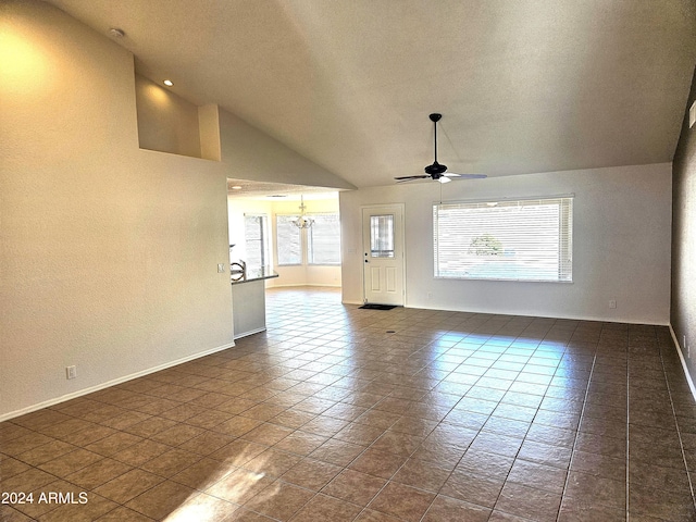 unfurnished living room with dark tile patterned flooring, ceiling fan with notable chandelier, a textured ceiling, and high vaulted ceiling