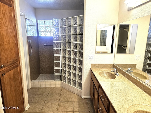 bathroom featuring a tile shower, tile patterned flooring, vanity, and a textured ceiling