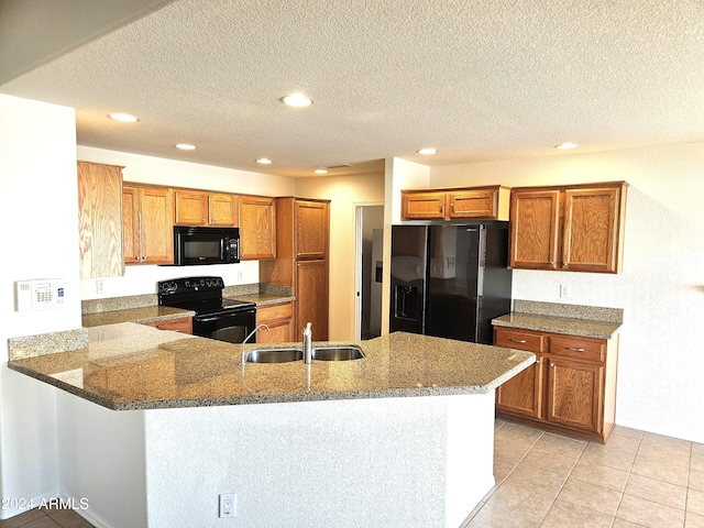 kitchen with sink, kitchen peninsula, dark stone countertops, a textured ceiling, and black appliances