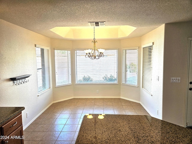 unfurnished dining area featuring light tile patterned floors, a tray ceiling, and a healthy amount of sunlight