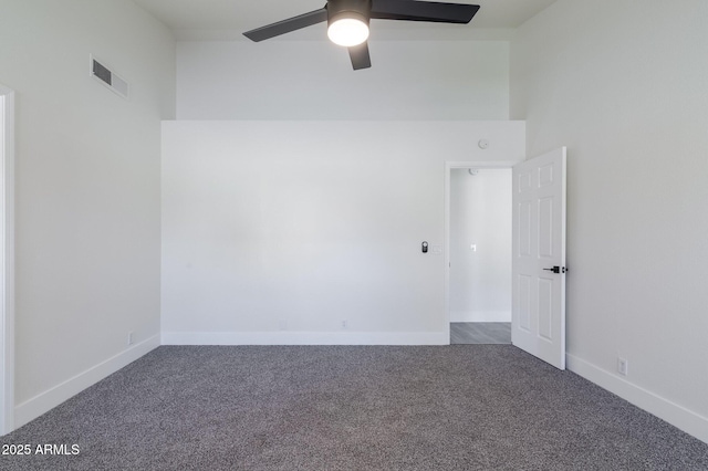 carpeted spare room with ceiling fan and a towering ceiling