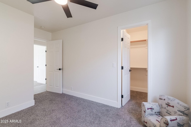 unfurnished bedroom with a walk in closet, ceiling fan, carpet floors, and a closet