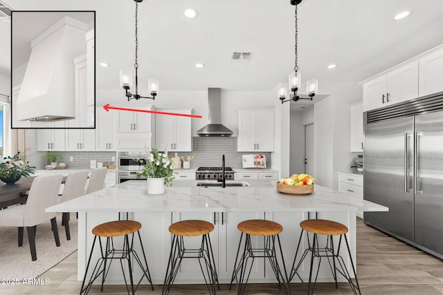 13947 E Barwick Dr, Scottsdale, AZ 85262 - kitchen with decorative backsplash, visible vents, wall chimney range hood, a notable chandelier, and appliances with stainless steel finishes