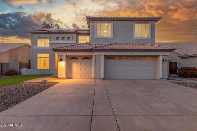 mediterranean / spanish-style house with fence, an attached garage, stucco siding, a tiled roof, and driveway