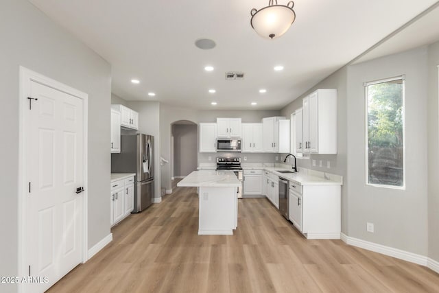 kitchen with visible vents, a sink, baseboards, arched walkways, and stainless steel appliances