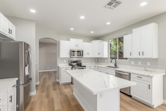 kitchen featuring light wood-type flooring, a sink, appliances with stainless steel finishes, and arched walkways