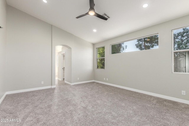carpeted empty room featuring arched walkways, ceiling fan, recessed lighting, and visible vents