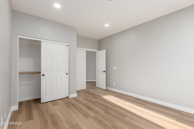 unfurnished bedroom featuring recessed lighting, baseboards, a closet, and light wood-type flooring