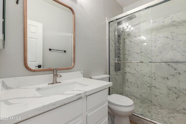bathroom with a marble finish shower, vanity, and toilet
