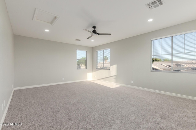 carpeted spare room featuring baseboards, visible vents, and attic access