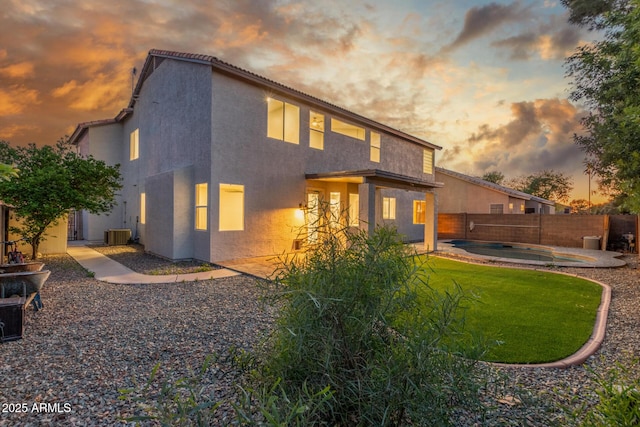 rear view of house with stucco siding, a fenced backyard, a fenced in pool, a patio, and a yard