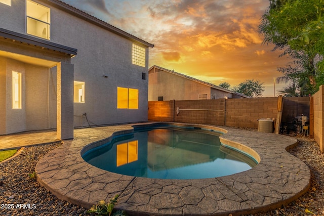 pool at dusk featuring a fenced in pool, a fenced backyard, and a patio area