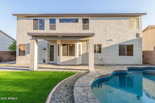 back of house with a yard, a fenced backyard, a patio area, and stucco siding