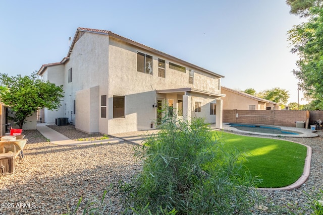 back of house with a fenced backyard, stucco siding, a fenced in pool, central AC unit, and a tile roof