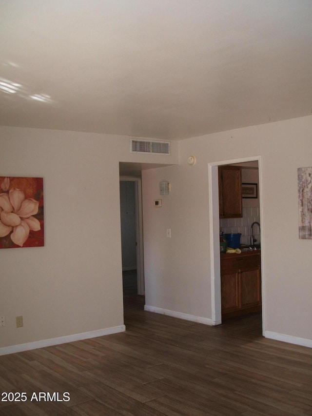 spare room with sink and dark wood-type flooring