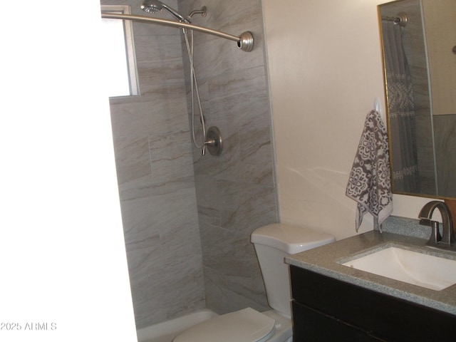 bathroom featuring vanity, toilet, and a tile shower