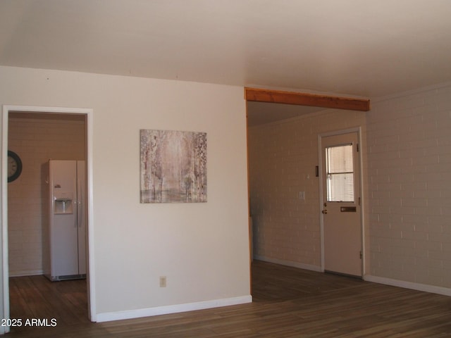 unfurnished room with dark hardwood / wood-style flooring and brick wall