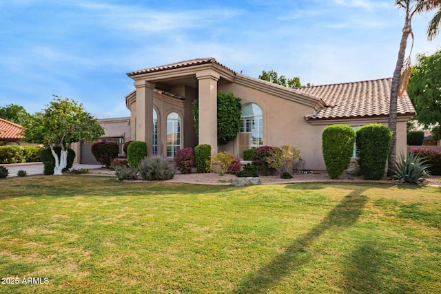 view of front of home featuring a tile roof, a front yard, and stucco siding