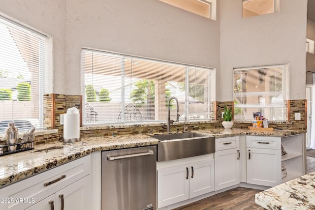 kitchen featuring a sink, decorative backsplash, dishwasher, and white cabinetry