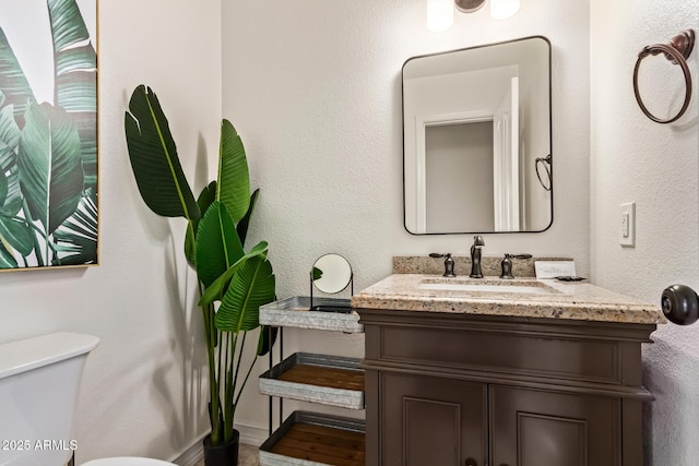 bathroom featuring baseboards, vanity, and toilet