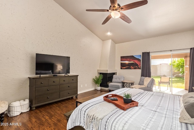 bedroom with access to outside, a large fireplace, wood finished floors, lofted ceiling, and a textured wall