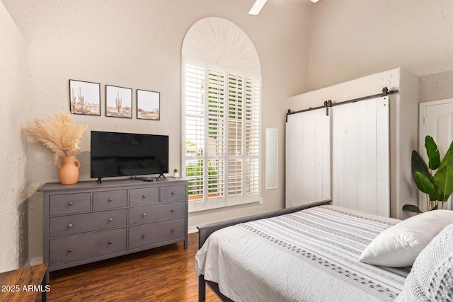 bedroom with a ceiling fan, dark wood finished floors, and a barn door