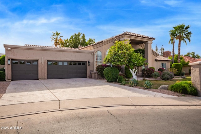 mediterranean / spanish house with concrete driveway, an attached garage, a tile roof, and stucco siding