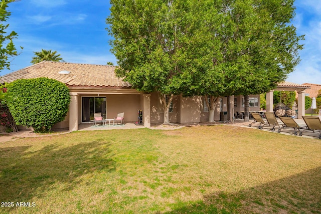 rear view of property featuring a patio area, stucco siding, a yard, and a tile roof