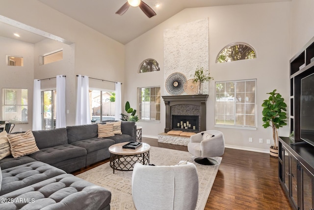 living area featuring dark wood-style flooring, high vaulted ceiling, a ceiling fan, and baseboards