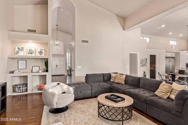 living room featuring arched walkways, high vaulted ceiling, visible vents, and dark wood-style floors