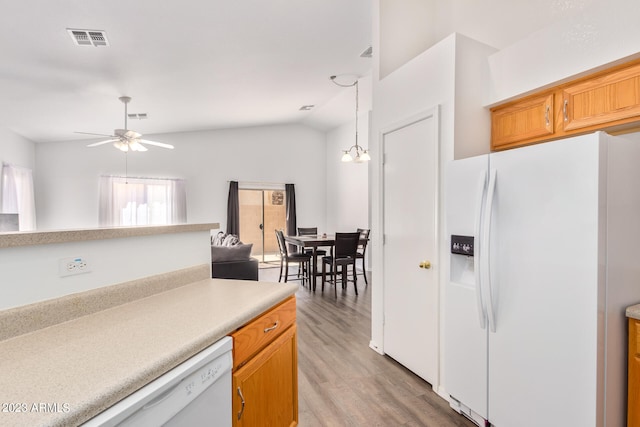 kitchen featuring decorative light fixtures, light hardwood / wood-style flooring, vaulted ceiling, white appliances, and ceiling fan with notable chandelier