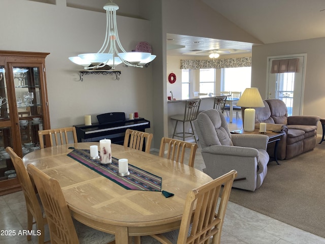 carpeted dining space with ceiling fan and vaulted ceiling