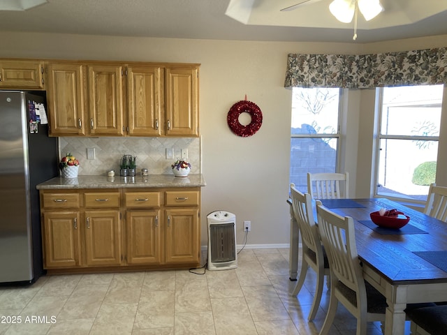 kitchen featuring backsplash, light tile patterned floors, stainless steel fridge, and ceiling fan