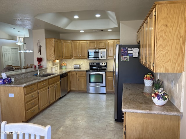 kitchen with stainless steel appliances, a tray ceiling, sink, and backsplash