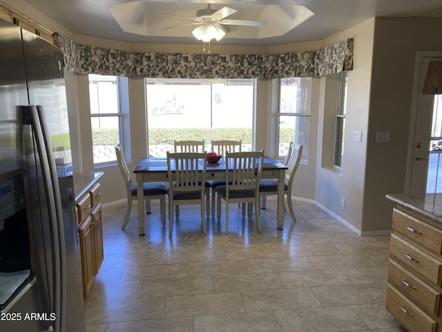 dining area featuring a raised ceiling and ceiling fan