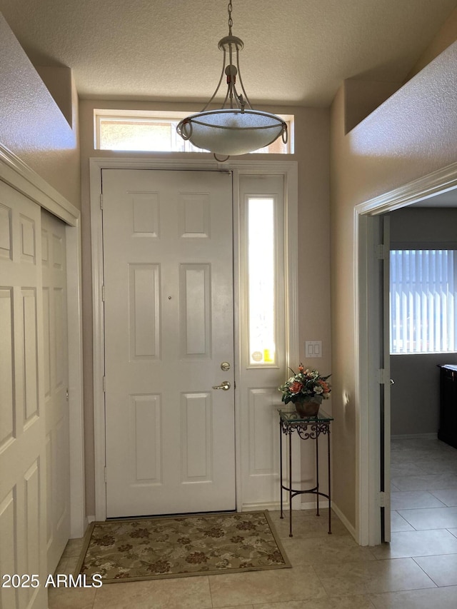 foyer entrance featuring light tile patterned floors and a textured ceiling