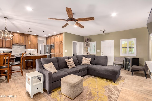 living room featuring ceiling fan, sink, and light wood-type flooring