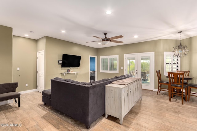 living room with ceiling fan with notable chandelier, french doors, and light hardwood / wood-style flooring