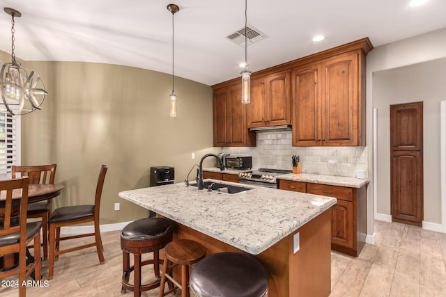 kitchen featuring sink, hanging light fixtures, a center island with sink, and stainless steel range with gas stovetop