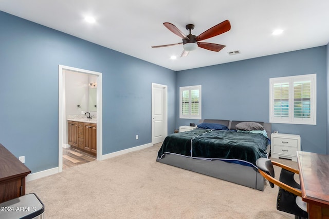 bedroom with multiple windows, ensuite bathroom, ceiling fan, and light colored carpet