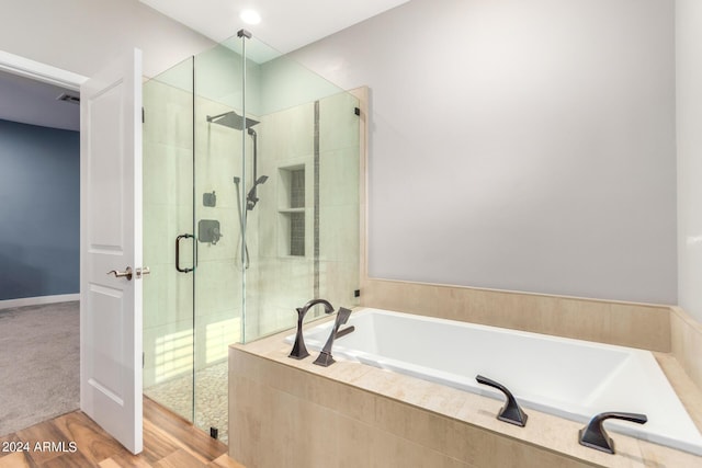 bathroom featuring plus walk in shower and wood-type flooring