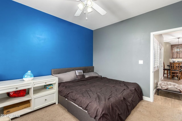 bedroom with light carpet and ceiling fan with notable chandelier